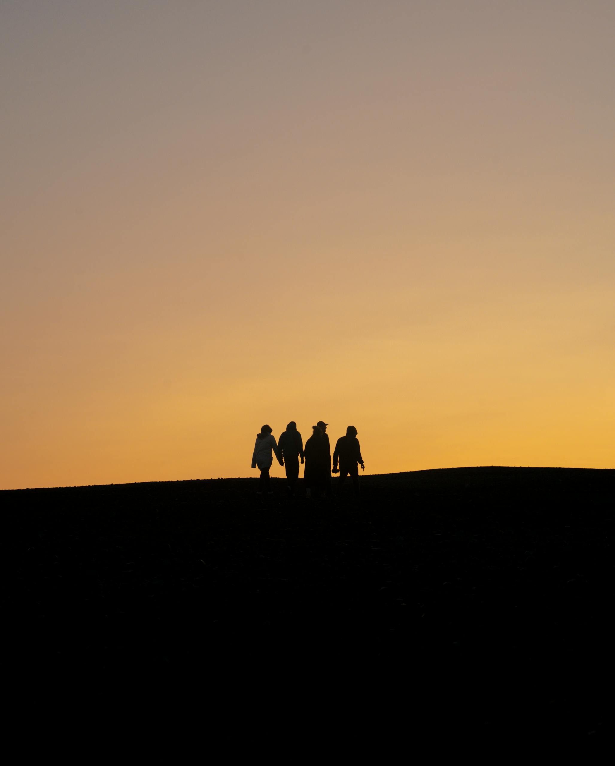A silhouette of four people walking at sunset against a stunning Icelandic sky.